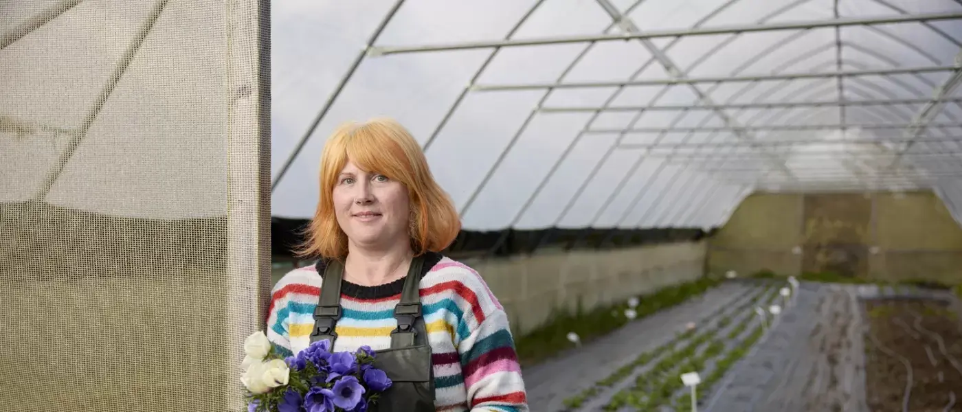 Woman with orange hair holding a bunch of white and purple flowers standing