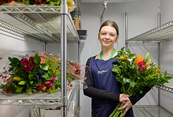 Floristry student in chiller cabinet with bouquet of flowers