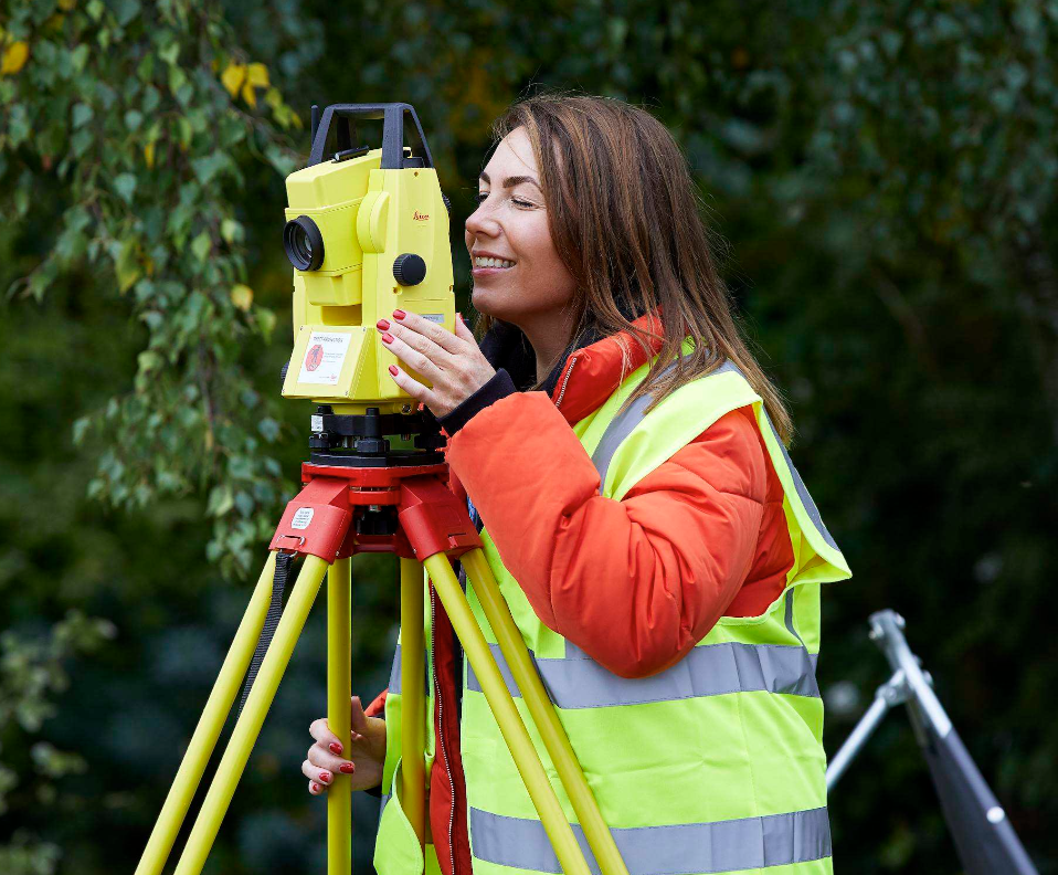 Mature student using theodolite for construction surveying