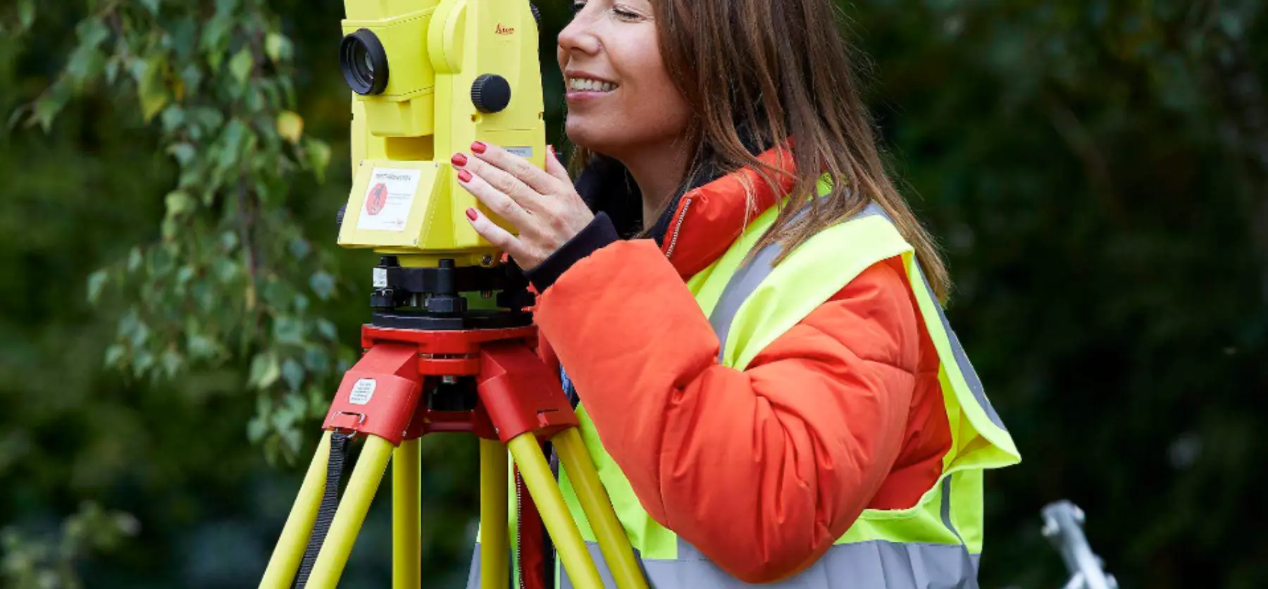 Mature student using theodolite for construction surveying
